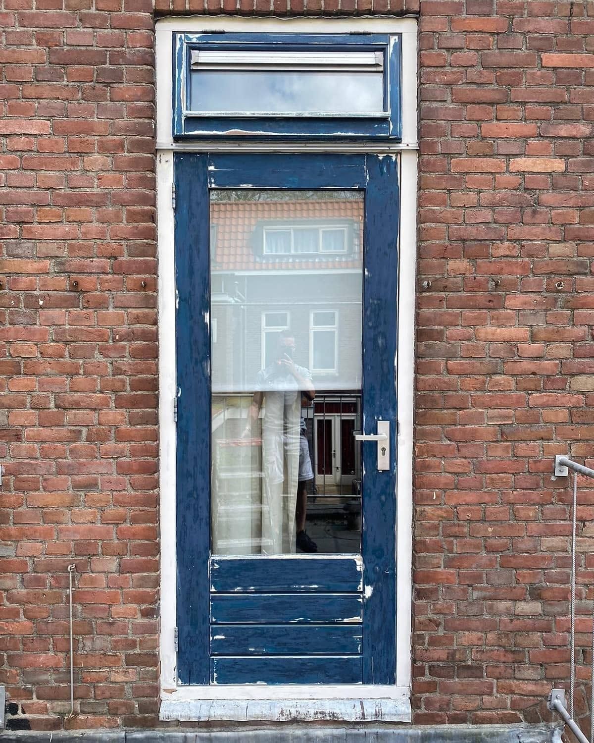 Voor: smalle deur met bovenlicht en afgebladderde verf